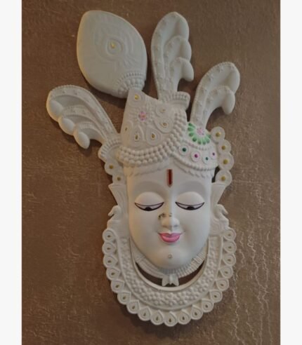 An original white wall sculpture titled 'Divine Grace', featuring an intricately detailed deity face with traditional motifs.