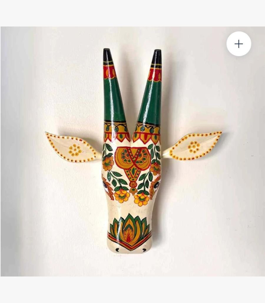 Hand-Painted Indian Folk Art Bull Mask A handcrafted wooden bull head wall sculpture featuring vibrant traditional Indian folk art motifs and floral patterns on a cream background.