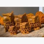 A set of five artisan-crafted wooden owl figurines eaturing detailed lattice carving and natural wood grain finishes.