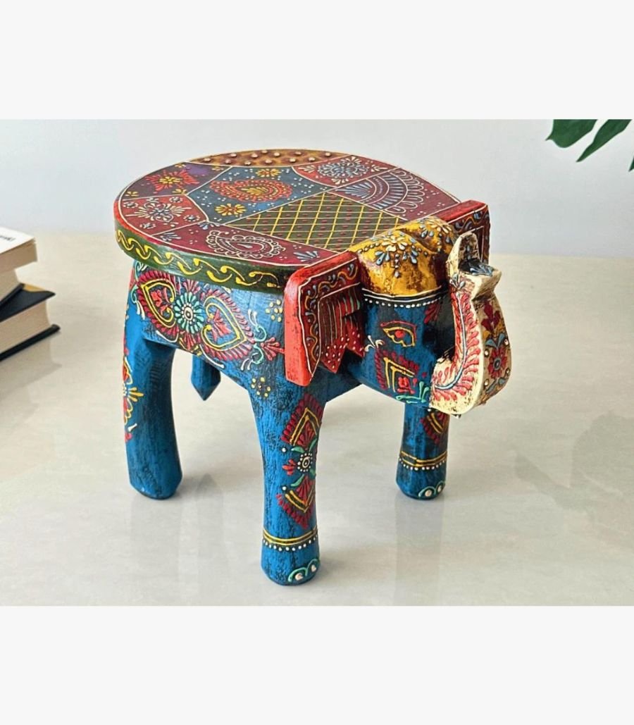 Hand-Painted Royal Elephant Stool by Rajasthan Heritage Artisans A vibrant, hand-painted wooden elephant stool featuring intricate traditional Indian floral patterns in blue, red, and gold, used as decorative accent furniture.