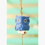A charming hand-carved blue wooden owl sculpture hanging from a jute rope, suitable for bohemian or nursery wall decor.