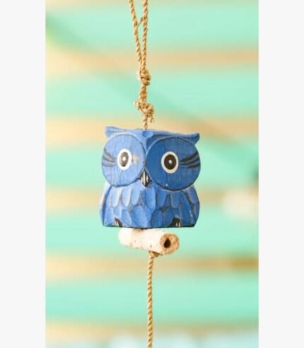 A charming hand-carved blue wooden owl sculpture hanging from a jute rope, suitable for bohemian or nursery wall decor.