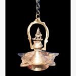 A handcrafted gold-finish brass pooja bell featuring an etched lotus petal handle and a sacred Rudraksha bead in a red velvet gift box.