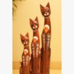 A set of three hand-carved mahogany wooden cat sculptures of varying heights, decorated with intricate dot-work patterns and jute accents.