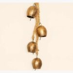 Handcrafted rustic brass bells with a distressed golden finish suspended from a natural braided jute rope for spiritual home decor.