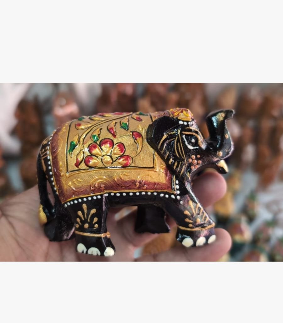 Hand-Painted Wooden Elephant Figurine A miniature wooden elephant figurine intricately hand-painted with traditional gold, red, and black floral patterns, held in a palm.