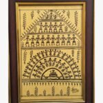 A detailed Warli tribal painting by Kena Anshuman featuring tiered rows of dancers and musicians in black marker on a golden-yellow background.
