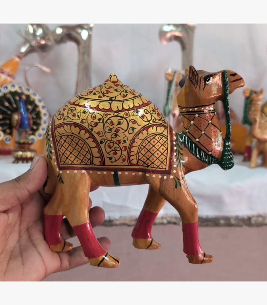 Hand-Painted Decorative Wooden Camel A close-up of a handcrafted wooden camel figurine, featuring detailed gold-leaf style floral painting and vibrant red leg accents.