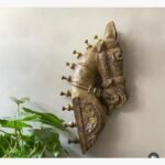 A hand-carved antique wooden horse head wall sculpture with a distressed gilded gold finish and traditional ceremonial harness details.