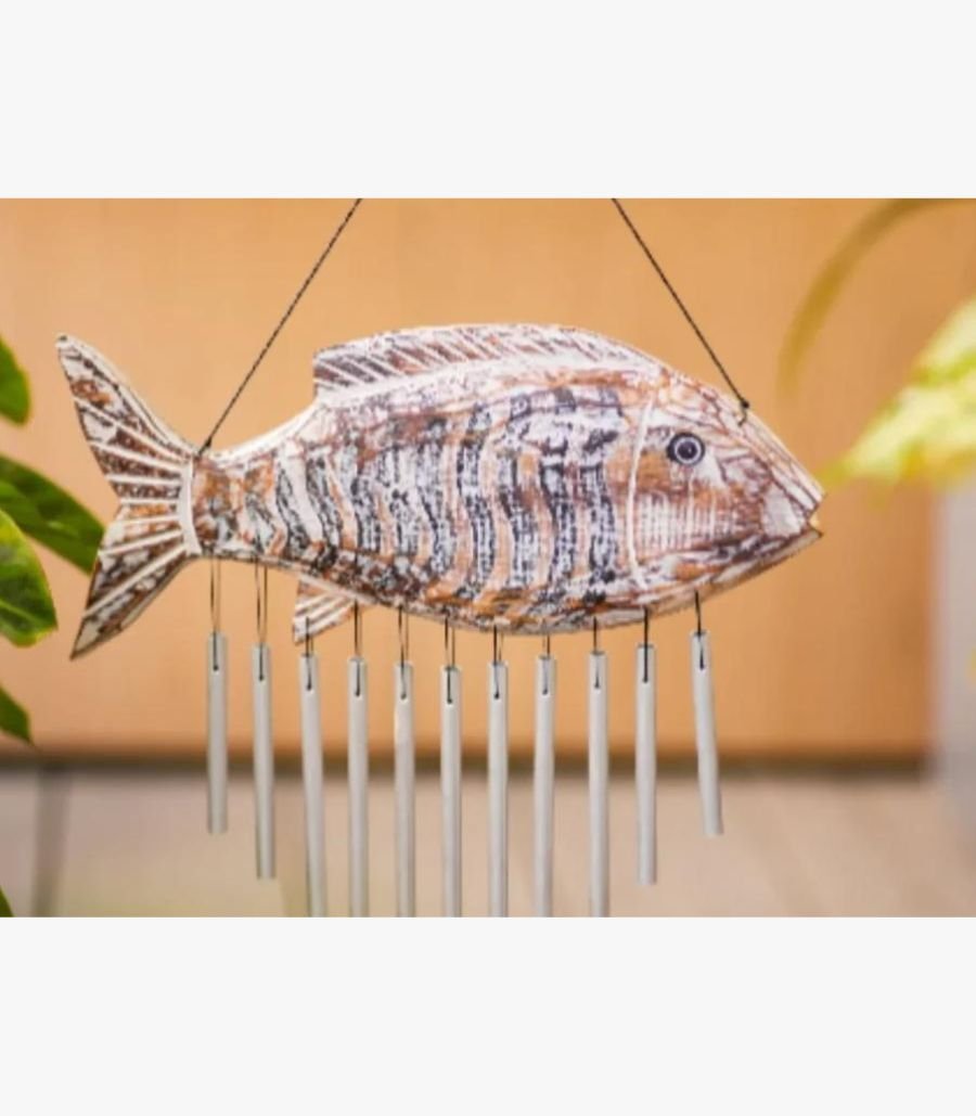 Aura Coastal Hand-Carved Wooden Fish Chime A hand-carved wooden fish wind chime with a distressed white and brown finish featuring hanging metallic chimes for coastal home decor.