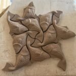 An original sculpted relief wall piece titled 'Aquatic Harmony' featuring a geometric tessellation of interlocking fish figures in a clay-toned finish.