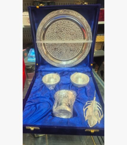 A premium 5-piece Ornate German Silver Pooja Thali set featuring an etched ritual plate, bowls, a pedestal diya, and a feather-shaped applicator in a velvet presentation box.