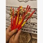 Handcrafted ritual gungroo wands wrapped in red and yellow silk thread with polished brass bells for traditional ceremonies.