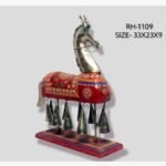 Handcrafted royal Rajasthani horse metal sculpture table decor featuring a red painted body with ornate gold patterns and hanging brass bells on a stable wooden base.
