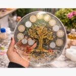 Handcrafted circular mixed media wall art panel titled Chakra Shrinidhi by Vina Bhavsar featuring a golden reflective tree of life accented with authentic Indian coins and shimmering crystal beads under clear resin.