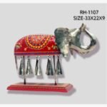 Handcrafted royal Rajasthani Ambabari elephant metal sculpture for table decor featuring an ornate red painted saddle and hanging brass bells on a sturdy pedestal.