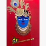 Handcrafted traditional Shrinathji mixed media relief wall art titled Divine Shrinathji featuring a blue face icon with an ornate gold mukut, peacock feather, and holy bansuri flute on a solid red background panel.