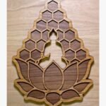 Handcrafted 3D layered wooden wall art titled Honeycomb Buddha Serenity showing a central silhouette cut-out of a meditating Buddha emerging from a lotus blossom base below a geometric honeycomb lattice backdrop.