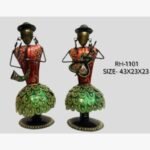 Handcrafted tribal musicians duo metal sculpture set featuring two stylized iron figures in green peacock pattern skirts playing a horn and string instrument.