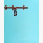 Timeworn Reflections realistic acrylic painting by Harshita Siddhpura showcasing an intricate rusty metal door latch mechanism against a vibrant solid cyan blue background.