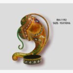 Handcrafted wrought iron traditional Indian Ganesha abstract face tealight candle holder titled Divine Contour by Crafts Heritage featuring a warm ochre and orange body with green scrollwork and a circular base container.