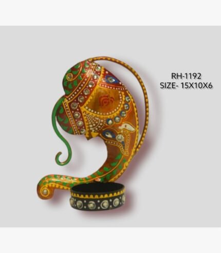 Handcrafted wrought iron traditional Indian Ganesha abstract face tealight candle holder titled Divine Contour by Crafts Heritage featuring a warm ochre and orange body with green scrollwork and a circular base container.