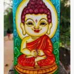 Hand-painted terracotta vase titled Cosmic Buddha by Akshaya Sivadas featuring a colorful illustration of a serene meditating little Buddha with a golden halo.