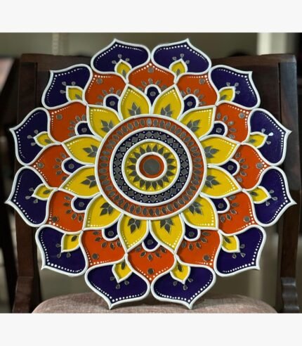 Handcrafted circular Lippan art wall hanging featuring royal purple, orange, and yellow scalloped lotus mandala patterns with mirror work by artist Rucha Desai.