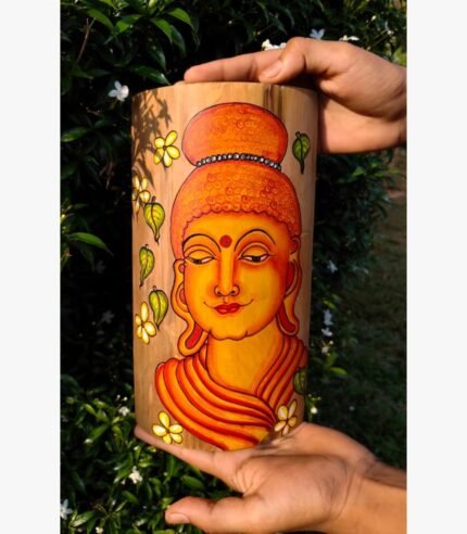 Hand-painted bamboo container titled Serene Buddha by Akshaya Sivadas featuring a detailed warm yellow and orange portrait of Lord Buddha in a traditional mural style flanked by small yellow flowers and green leaves.