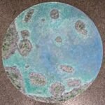 An original round circular aerial ocean artwork on canvas featuring turquoise water, foaming waves, and rocky islands by artist Jyoti Machigad.