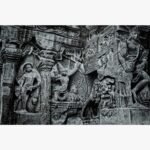 Highly detailed monochrome charcoal and graphite sketch titled Ellora Caves (Heritage) by Bharti Parmar depicting the intricate ancient rock-cut architecture and stone deity reliefs of the historic Ellora complex.