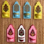 Handcrafted wooden royal jharokha wall brackets with floral motifs in pastel yellow, sky blue, pink, and white painted by artist Rucha Desai.