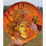 Hand-painted decorative wall plate titled Ardhanarishvara Harmony by Akshaya Sivadas featuring a traditional Kerala mural portrait of Lord Shiva and Goddess Parvati split vertically on a circular terracotta base.