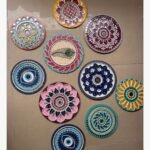 Handcrafted Lippan art wall plate set featuring evil eye motifs, peacock feather designs, and lotus mandalas with mirror work by artist Rucha Desai.