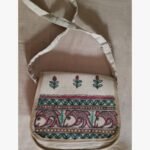 A hand-painted Madhubani folk art fabric sling bag featuring traditional Indian fish motifs and floral borders by artist Bhavna Mishra.