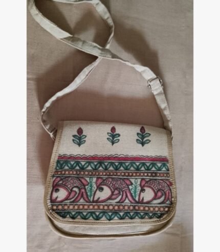 A hand-painted Madhubani folk art fabric sling bag featuring traditional Indian fish motifs and floral borders by artist Bhavna Mishra.