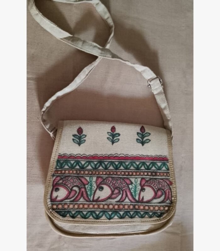 A hand-painted Madhubani folk art fabric sling bag featuring traditional Indian fish motifs and floral borders by artist Bhavna Mishra.