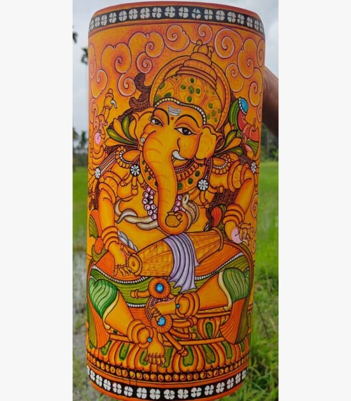 Hand-painted terracotta vase titled Mridangam Ganesha by Akshaya Sivadas featuring a detailed yellow Lord Ganesha playing a traditional drum on a golden ochre background.