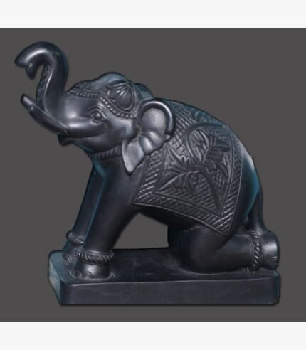 A polished black stone elephant sculpture with its trunk raised, featuring traditional carved blankets and ornaments, mounted on a solid rectangular base.