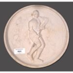Hand-carved Dhrangadhra beige sandstone circular relief panel titled Hockey Player by Mangalya Stone Panels showcasing an athlete in motion with a hockey stick and ice skates.