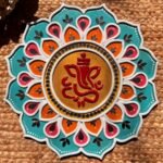 Handcrafted circular Lord Ganesha Lippan art wall hanging with teal and orange lotus petals, mirror work, and central gold motif by Rucha Desai.