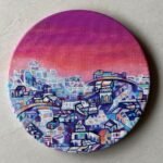 Circular acrylic painting titled The Warmth of Cityscape by Payal Dubey depicting a colourful architectural landscape under a twilight sky.